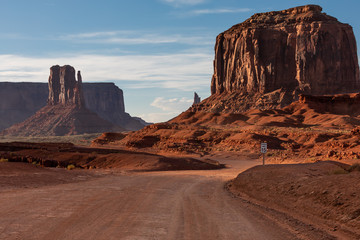 In the Monument Valley just before sunset, a dirt road snakes through the mesas