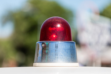 Close up of an old red police car siren, against a bokeh background