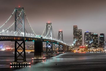 Night shot of San Francisco skyline, with the Bay Bridge in the foreground and skyscrapers in the background