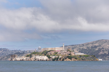 Fototapeta na wymiar Close up of the Alcatraz island in San Francisco bay, under a blue sky with thick puffy clouds