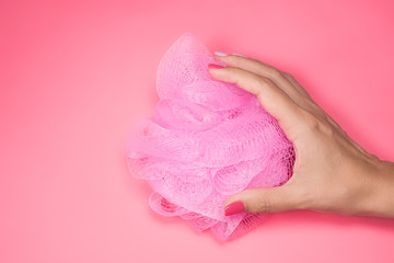 Closeup view of female hands holding new just bought pink bright modern round scrubber pouf bath...