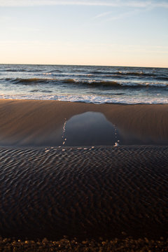 Golden Hour Waves and Reflective Wet Sand on a Serene Beach