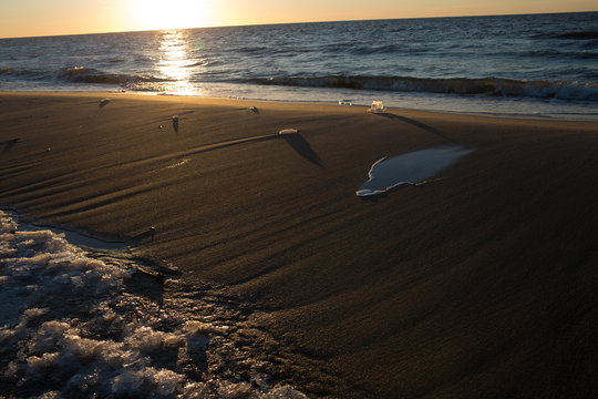 Golden Sunset Glow Over Rippled Beach Sand and Ocean