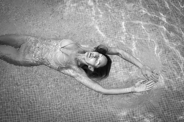 Black and white portrait of a beautiful woman swimming in a pool