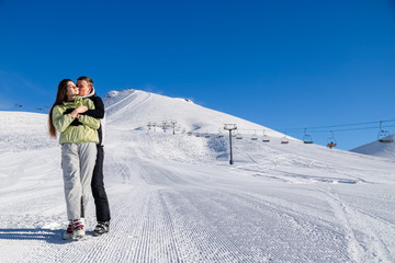 Fototapeta na wymiar Happy couple in snowing mountains, active lifestyle, winter vacation, luxury wintertime resort, loving family, cold weather