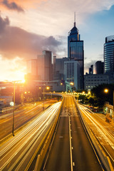 Fototapeta premium Light trails of traffic in Hong Kong at sunset time with Hong Kong bussines center in background. Asia. Asian tourism, modern city life, or business finance and economy concept