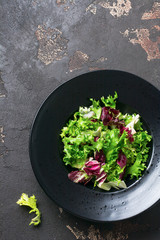 Mix fresh leaves of arugula, lettuce, spinach, beets for salad on a dark stone background. Selective focus.
