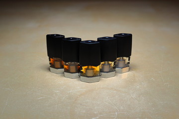 e-juice vape refill pods with liquids of different shades of orange arranged to form a gradient, isolated close up