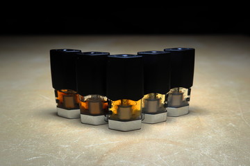 e-juice vape refill pods with liquids of different shades of orange arranged to form a gradient, isolated close up
