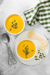 Autumn pumpkin cream soup with seeds. Light grey background