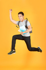 Fototapeta na wymiar Student man jumping with backpack isolated on orange background