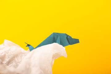 whale on a wave handmade origami craft paper art on a yellow paper background
