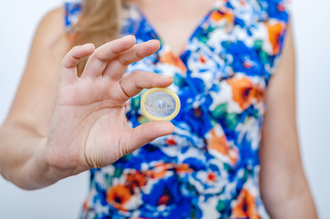 Woman in colored dress holds condom in hand without packaging, demonstrates on camera.