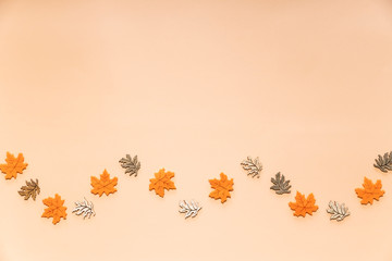 Golden leaves on beige background. Autumn, fall concept.