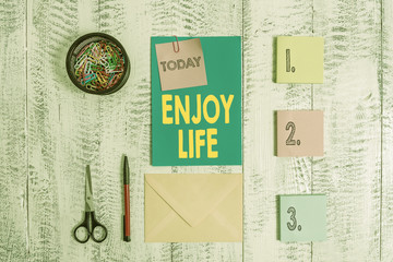 Word writing text Enjoy Life. Business photo showcasing Any thing, place,food or demonstrating, that makes you relax and happy Envelope letter sticky note ballpoint clips can scissors wooden