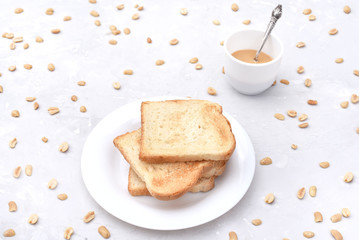 Fototapeta na wymiar A stack of toast with peanut butter and peanuts around on the table.