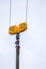 Crane hoisting block with hook on steel chain on the steel rope. Loading\unloading of building materials on construction building site.