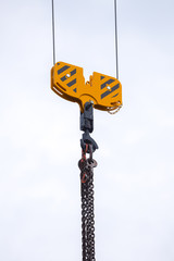 Fototapeta premium Crane hoisting block with hook on steel chain on the steel rope. Loading\unloading of building materials on construction building site.