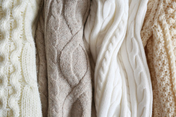 Bunch of knitted warm pastel color sweaters with different vertical knitting patterns hanging in bunch, clearly visible texture. Stylish fall / winter season knitwear clothing. Close up, copy space. - Powered by Adobe