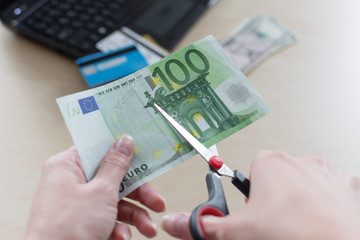 Cutting Euro banknote with a scissors, cut budget, reduce cost. Interest rates concept.