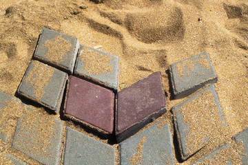 Destroyed path of paving stone on a sandy base