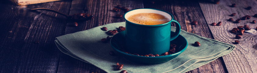 Cafe background with a green cup of espresso coffee standing on a linen napkin with a retro coffee grinder old book. Retro style Nashville. Tonted image. Banner.