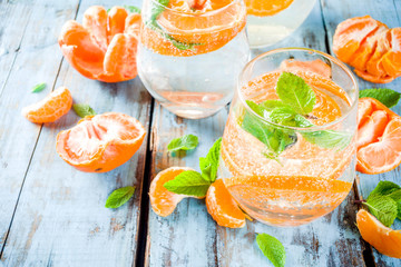 Summer tangerine citrus drink, lemonade or mojito, with fresh tangerines, lemons and mint on a blue...