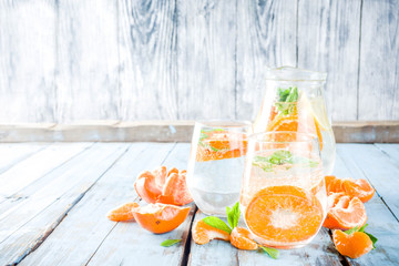 Summer tangerine citrus drink, lemonade or mojito, with fresh tangerines, lemons and mint on a blue wooden table,