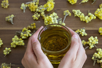 The Helichrysum Arenarium golden grass on the wooden background.