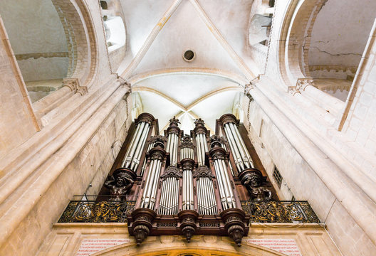 Wide angle symmetrical shot of a large pipe organ hosted in a french gothic church