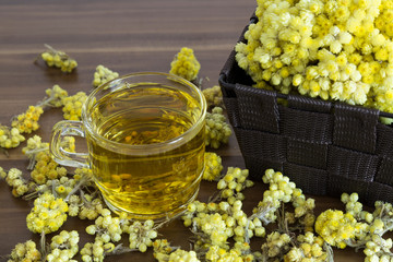 The Helichrysum Arenarium golden grass on the wooden background.