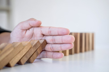 Risk and Strategy in Business, Image of hand stopping falling collapse wooden block dominoes effect from continuous toppled block, prevention and development to stability