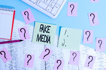 Conceptual hand writing showing Fake Media. Concept meaning An formation held by brodcasters which we cannot rely on Writing tools and scribbled paper on top of the wooden table