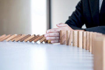 Risk and Strategy in Business, Image of hand stopping falling collapse wooden block dominoes effect...
