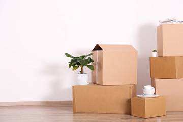 Bunch of blank unsigned moving boxes in new empty apartment. Spacious unfurnished room with unpacked cardboard box stack. Interior background, copy space for text.
