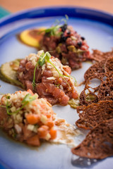 three different tartars on a blue plate