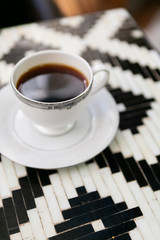 Cup of black coffee in vintage tea cup, black and white tile table, close up, modern cafe