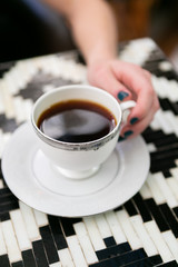 Girl holding cup of coffee in antique cup at cafe, close up, copy space