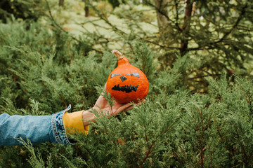 Halloween pumpkin. Woman holding a scary face pumpkin. Happy Halloween party holiday. Celebrate annual in October 31. Autumn season. Fall color, orange and yellow. Trick or treat. Young girl outdoors