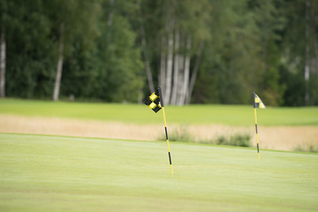 Two flags marking the holes in golf course. Empty emerald green fields, putting areas. Summer...