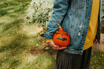 Halloween pumpkin. Woman holding a scary face pumpkin. Happy Halloween party holiday. Celebrate annual in October 31. Autumn season. Fall color, orange and yellow. Trick or treat. Young girl outdoors