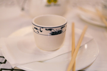 Mug sitting on a white plate next to chopsticks