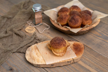 Homemade Muffins topped with Cinnamon Sugar in Rustic Setting; Wooden Bowl, Wooden Table, Cinnamon Sugar Jar in Background