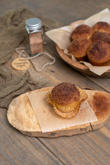 Obraz na płótnie Canvas Homemade Muffins topped with Cinnamon Sugar in Rustic Setting; Wooden Bowl, Wooden Table, Cinnamon Sugar Jar in Background