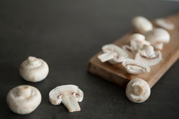 white mushrooms on wooden cutting board,  on dark background