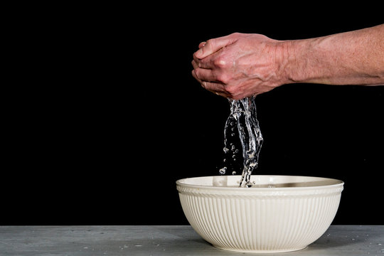 man washing his hands with water in white bowl, Dark background, copy space