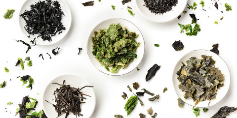 A panoramic overhead shot of a variety of dry seaweed, sea vegetables, on a white background