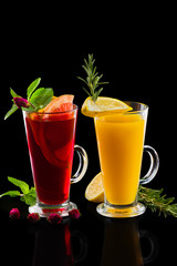 Two glasses of rose tea and  lemon tea with ginger and rosemary isoalted on black