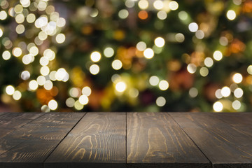 Wooden dark tabletop and blurred christmas tree bokeh. Xmas background for display your products.