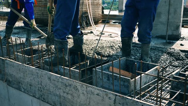 Builders level cement on a floor while working at a construction site.